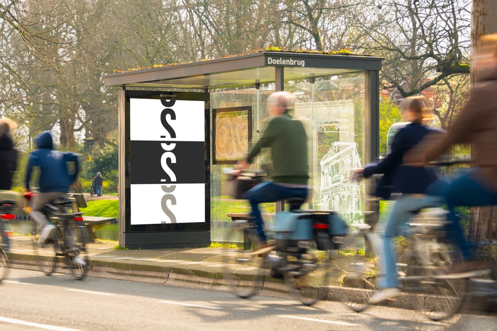 Fietsers rijden langs een verlichte abri bij een bushalte in een dorpse omgeving