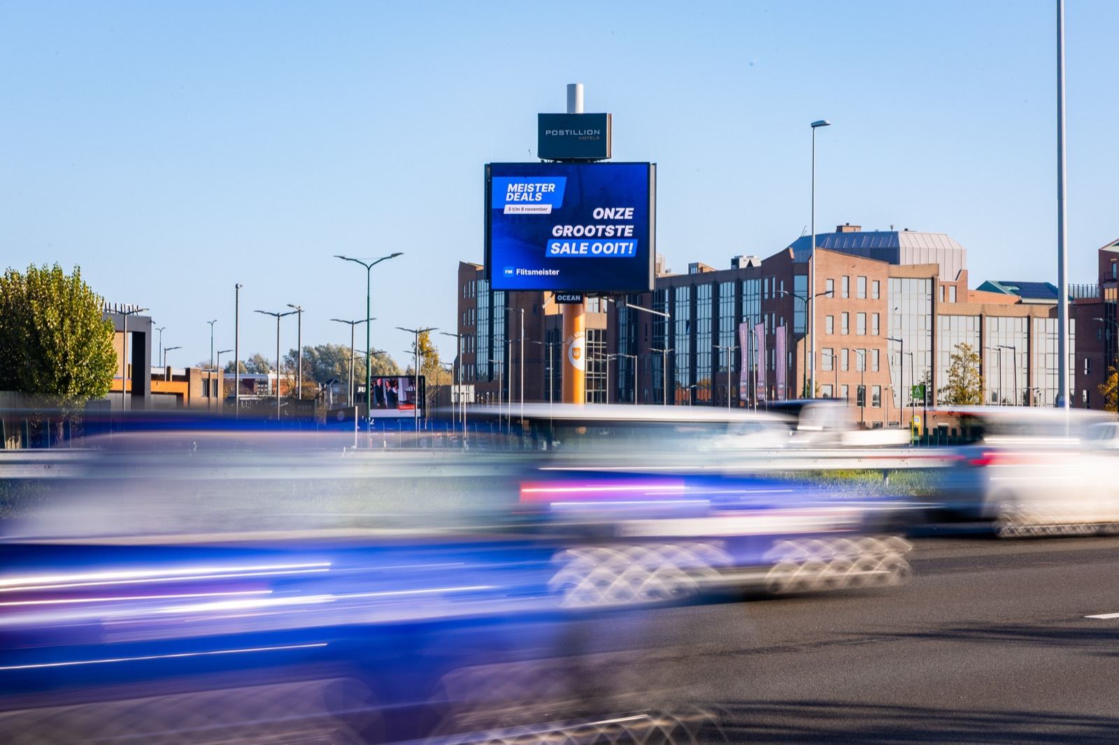 Digitale snelwegmast langs de A12 bij Bunnik met de Flitsmeister Meister Deals-uiting, met voorbijrazende auto's op de voorgrond
